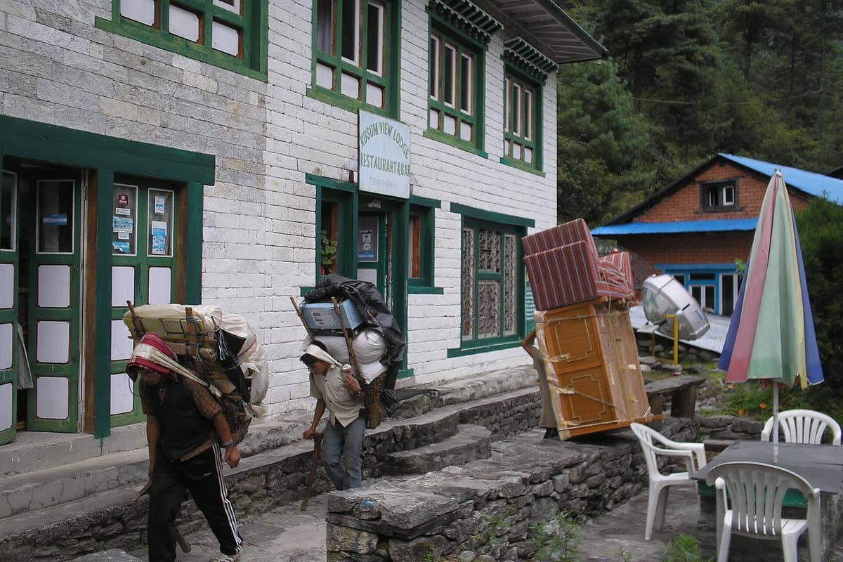 Porters carrying furniture and supplies outside a Khumbu lodge